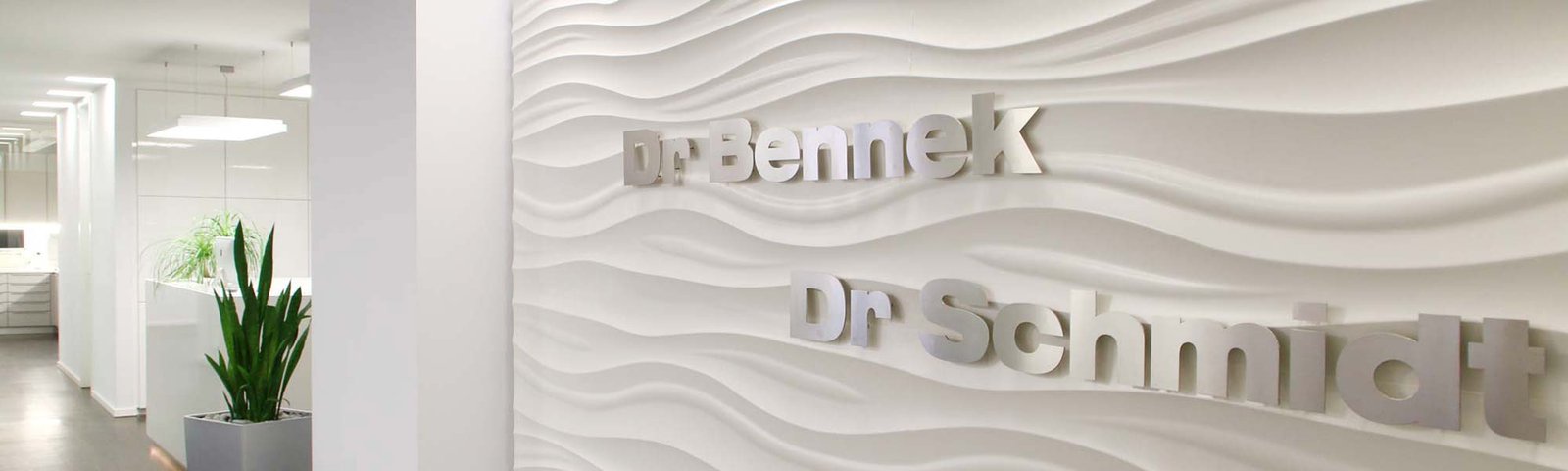 Empfangsbereich der Praxis mit dem Schriftzug Dr. Bennek und Dr. Schmidt